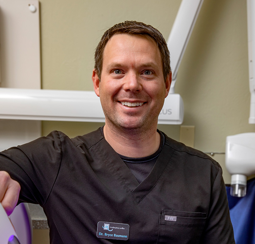 Lifestyle photography example of a dentist smiling at the camera. Dental equipment can be seen behind him.